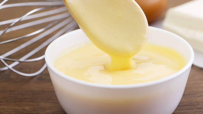 A light yellow sauce in a bowl with a spoon lifting it out