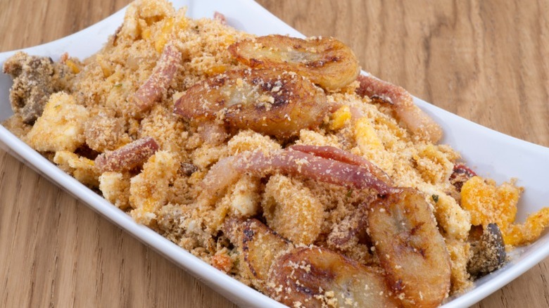 a plate of banana farofa on a wooden counter. Brazilian dish with toasted cassava flour