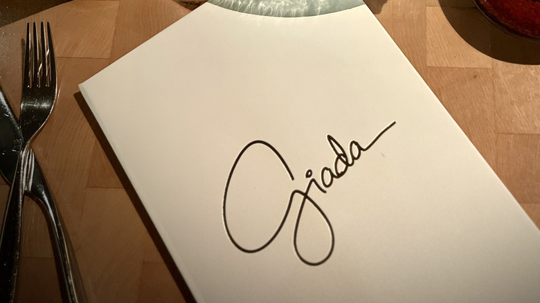 The menu at Giada on a wooden surface near utensils