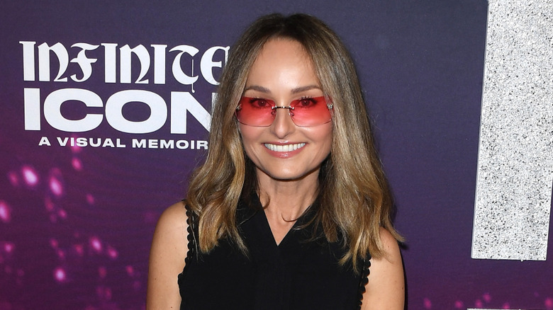 Giada De Laurentiis wearing pink sunglasses and smiling at a red carpet event.