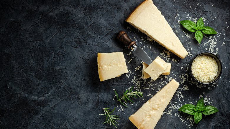 Top view of wedges of Parmesan cheese and a ramekin of grated Parmesan cheese