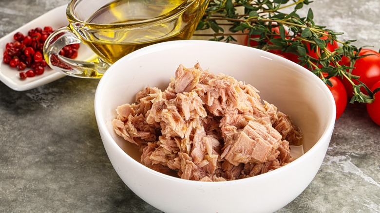 Tuna fillet in white bowl and oil in glass salad