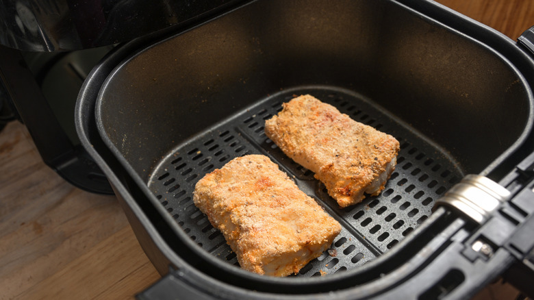 Breaded fish fillets in an air fryer basket.