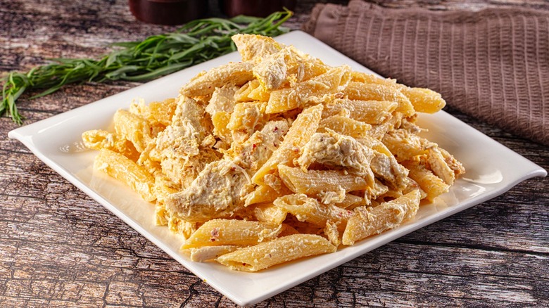 Chicken Alfredo with penne pasta on white square plate