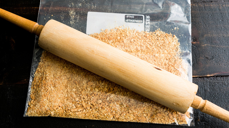 Making graham cracker crust with a rolling pin and the graham crackers in a ziploc bag