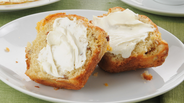 Halved muffin spread with butter on a plate