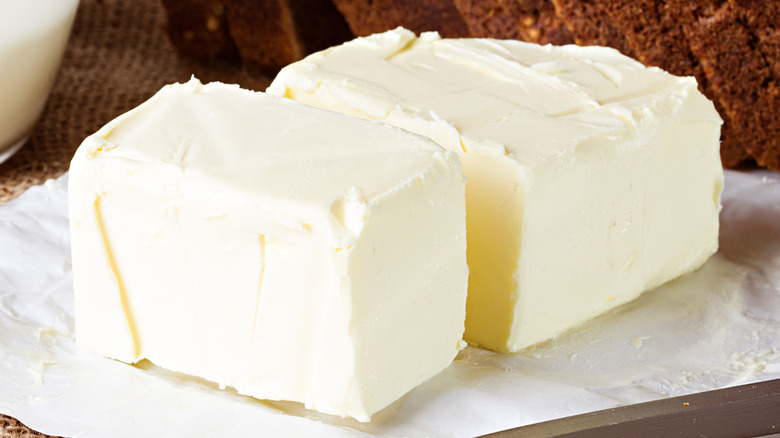Close up of a large block of butter split in half on wrapping paper