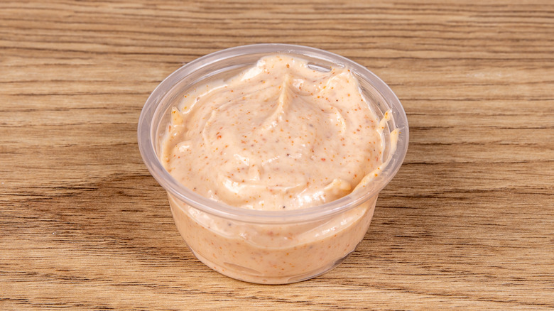 A closeup of roasted corn on the cob by a bowl of BBQ mayo sauce