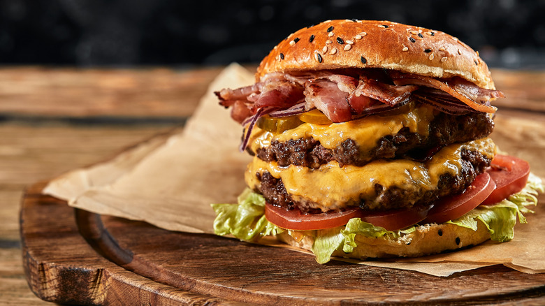 A large double cheeseburger with bacon, tomatoes, lettuce, and more