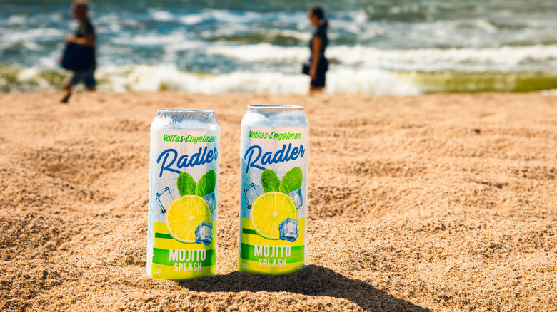 two canned cocktails stuck in sandy beach