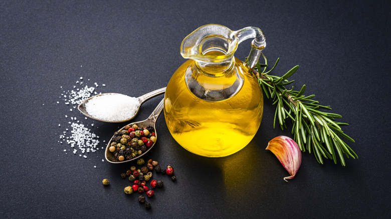 Oil, herbs, aromatics, and seasonings on a black surface