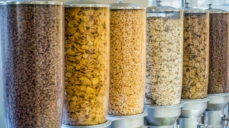 A row of cereal dispensers offering corn flakes and other cereals
