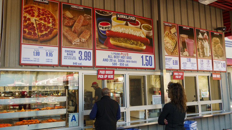 The exterior of an outdoor Costco food court with menu signs above the pick-up windows.