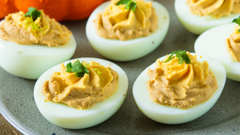 A plate of deviled eggs topped with parsley