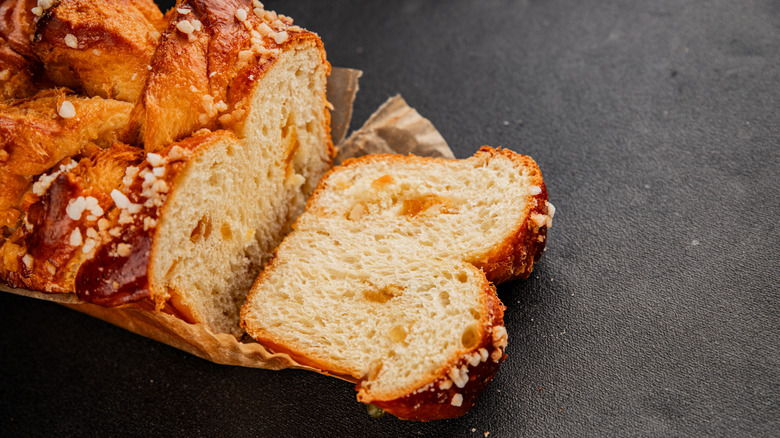 Sliced brioche on brown paper on a black surface