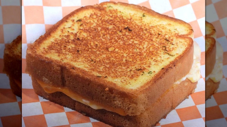 Grilled cheese sandwich made with Texas toast on checkered paper