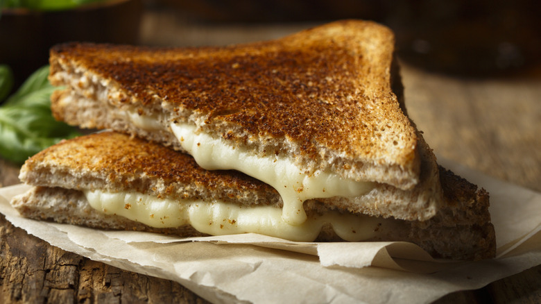 Halved grilled cheese sandwich on parchment paper