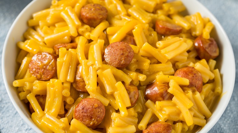 macaroni and cheese with sliced hot dogs in a white bowl
