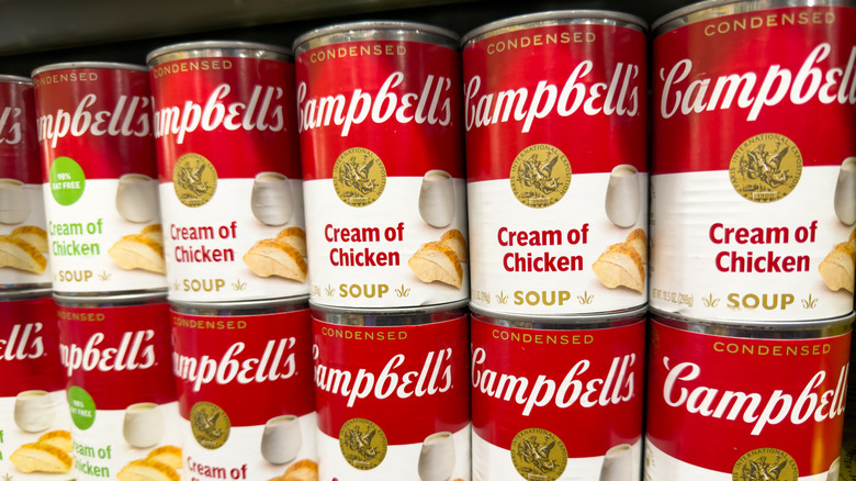 Cans of Campbell's Cream of Chicken soup stacked on a store shelf