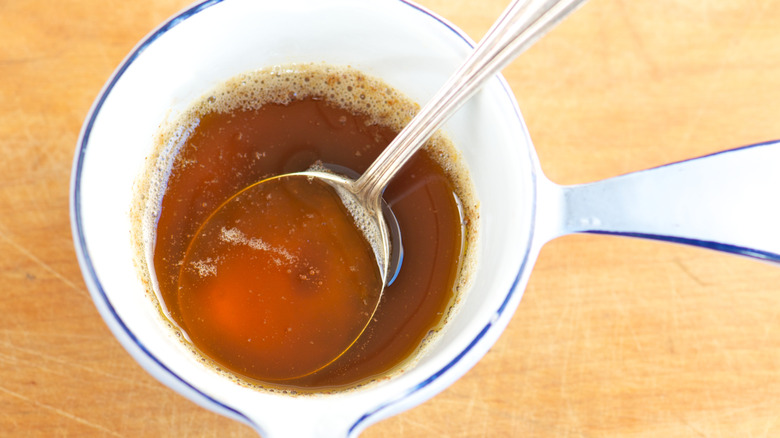A top-down view of brown butter in a pitcher with a spoon