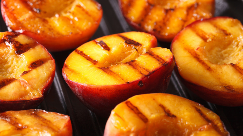 Close-up of halved peaches with grill marks, caramelized and seared on a grill pan.