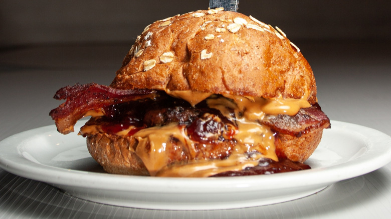 A burger topped with peanut butter, jelly, and bacon