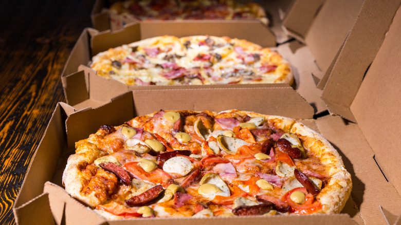 Different types of pizzas in their boxes on a table