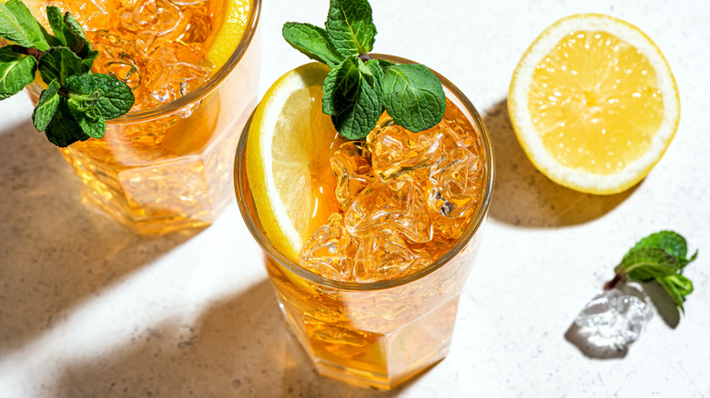 A glass of iced tea with lemon and mint and a wedge of fresh lemon