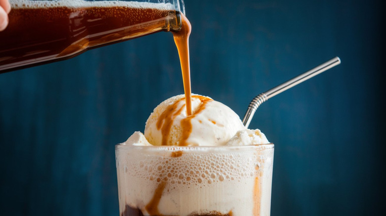 Root beer being poured across a scoop of ice cream for a root beer float