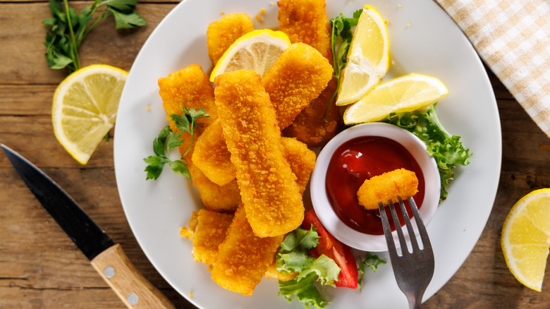 Fish sticks with lemon wedges and ketchup for dipping