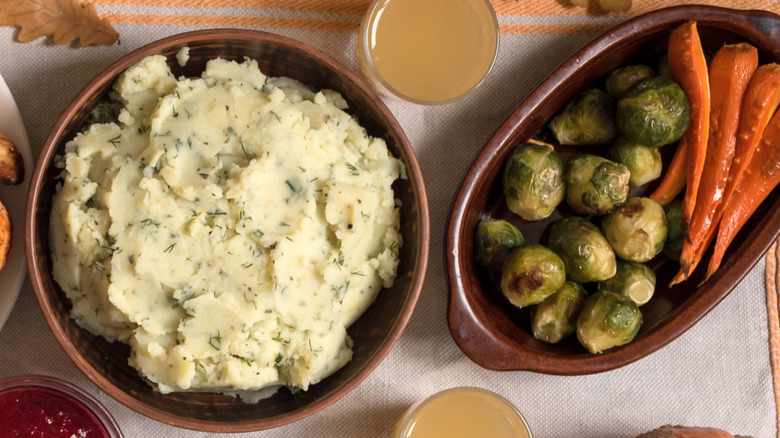 Dishes of herbed mashed potatoes, roasted Brussels sprouts, and roasted carrots