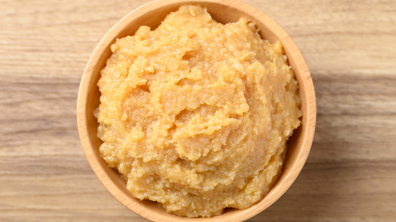 Top view of wooden bowl of white miso paste.