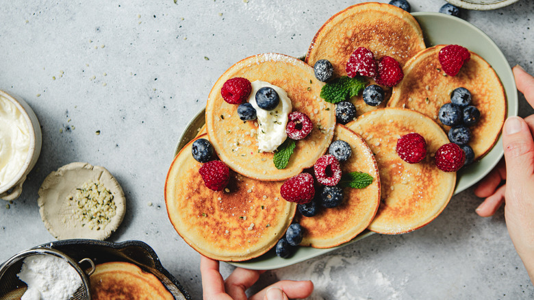 Overhead shot of pancakes spread out on a plate topped with berries