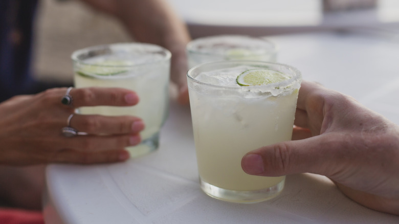 People holding glasses of margarita cocktails