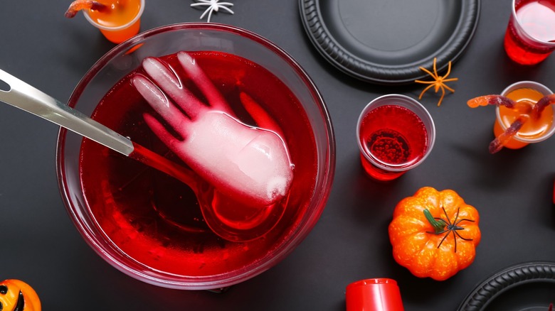 Punch bowl with large hand-shaped ice cube and Halloween decorations