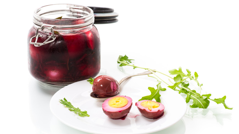 pink pickled eggs on a white plate and in an open jar