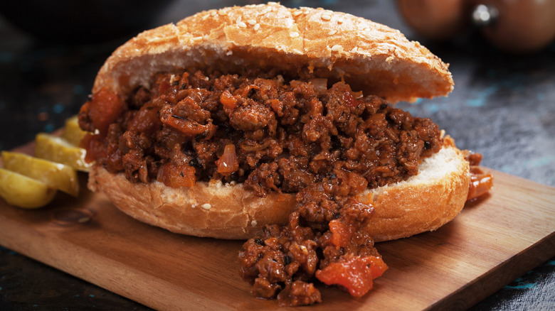 A large sloppy joe sandwich on a wooden board.
