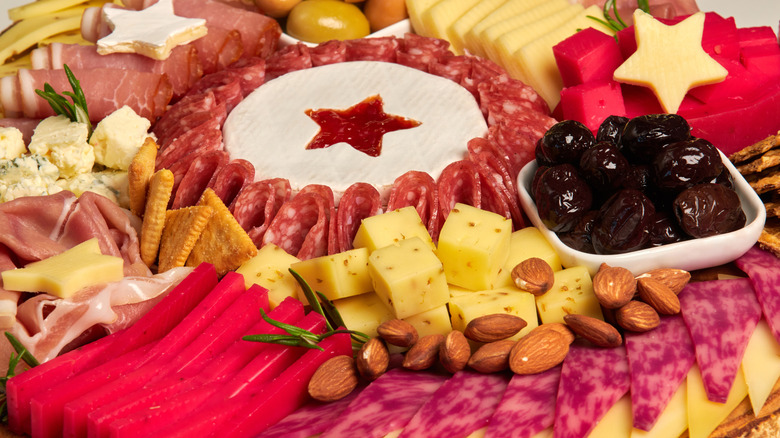 Charcuterie board with star-shaped cheese dip, slices of meat and cheese, nuts, and crackers