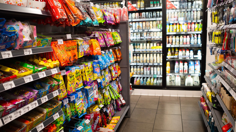 A convenience store aisle showing candy, sodas, drinks, and more