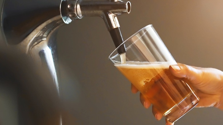 Person pouring beer from tap into glass