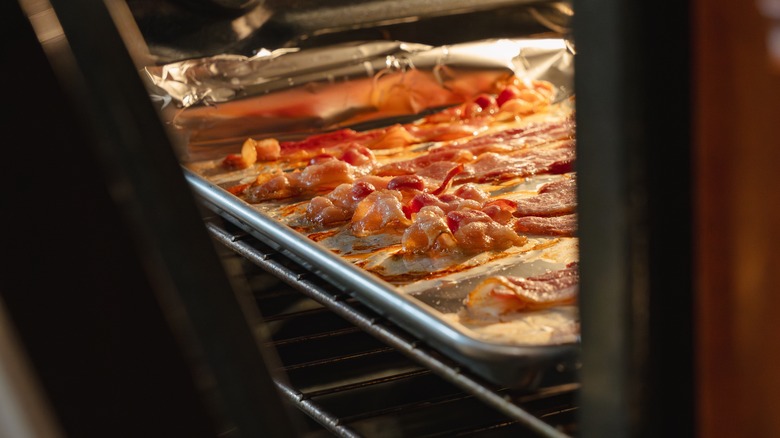 Bacon cooking on a tray in a slightly open oven