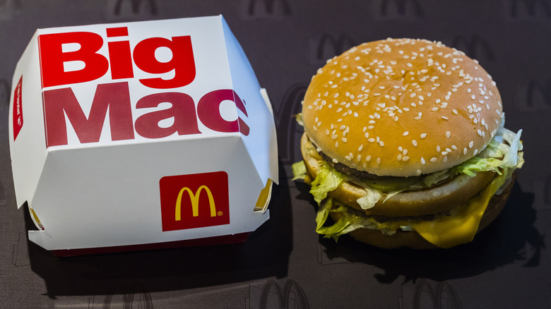 A Big Mac from McDonald's next to the closed cardboard box it came in.