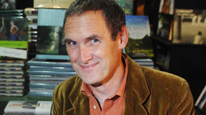 Food critic A.A. Gill smiling in front of several books.