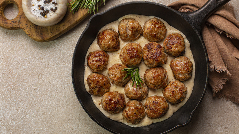 Meatballs within a creamy sauce in a cast iron skillet