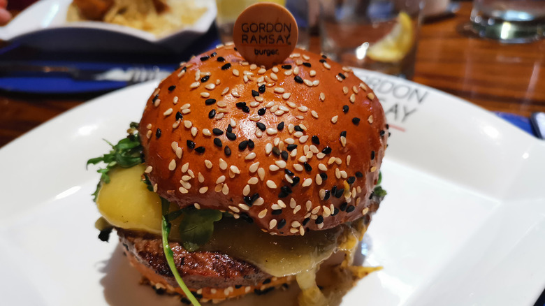 A closeup of a gordon ramsay burger on a plate with melted cheese