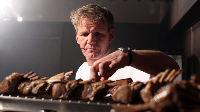 Chef Gordon Ramsay placing racks of lamb on a tray