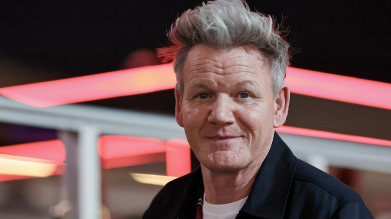 Gordon Ramsay smiles outside a restaurant at night