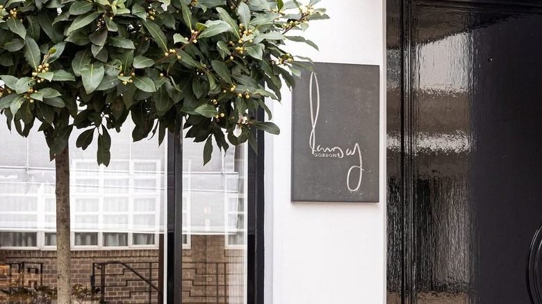 Subtle exterior outside restaurant gordon ramsay in London with signage in cursive letters and a small tree