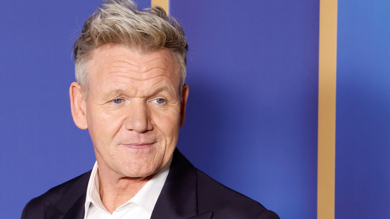 Gordon Ramsay standing in front of a purple background at an event