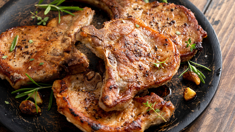 A pork chop served alongside a lemon and other foods